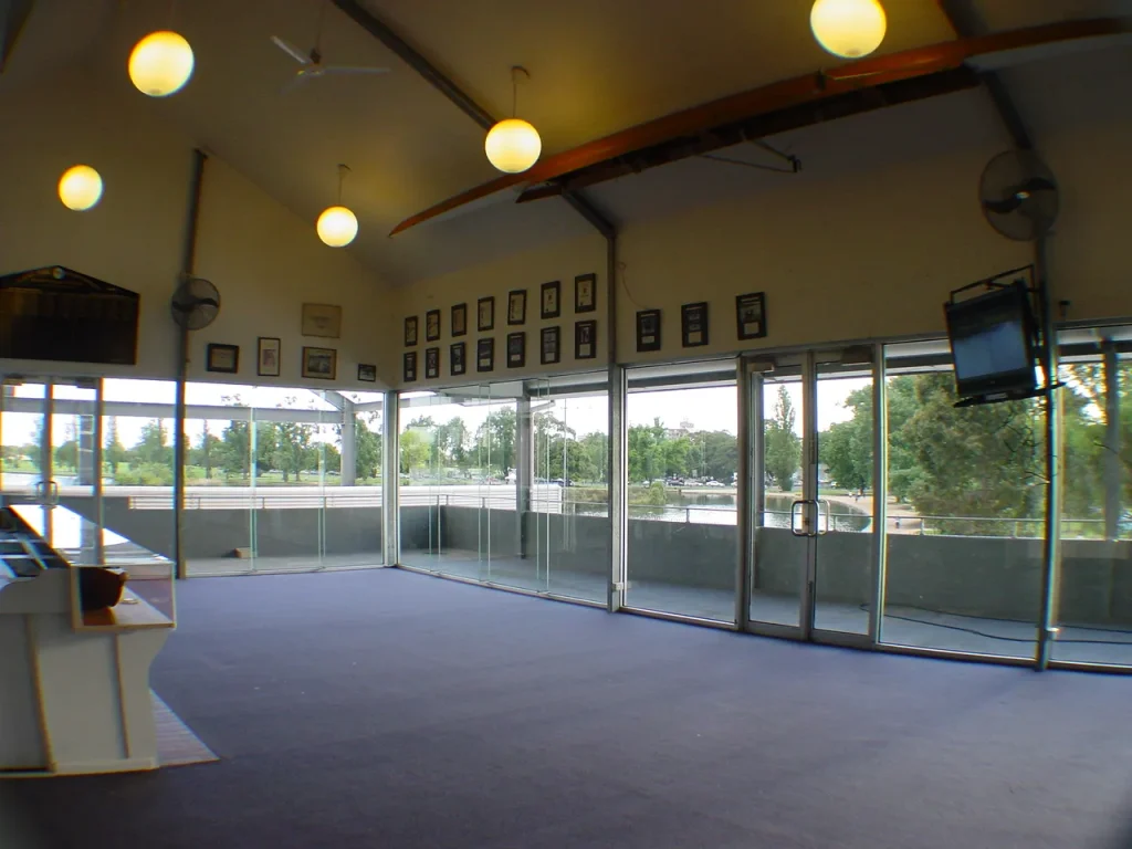 Light-filled indoor function space at Albert Park Rowing Club with floor-to-ceiling glass windows overlooking the lake.