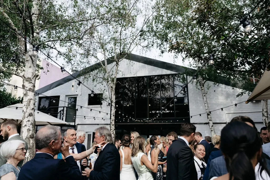 Guests enjoying an outdoor cocktail reception in the paved courtyard with festoon lighting outside Butler Lane in Richmond.