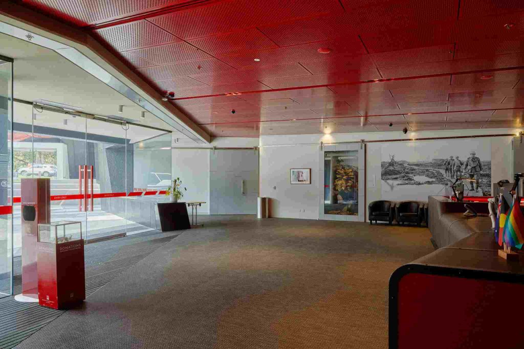Modern event foyer interior at the Shrine of Remembrance Visitors Centre featuring a striking red ceiling and sleek design.