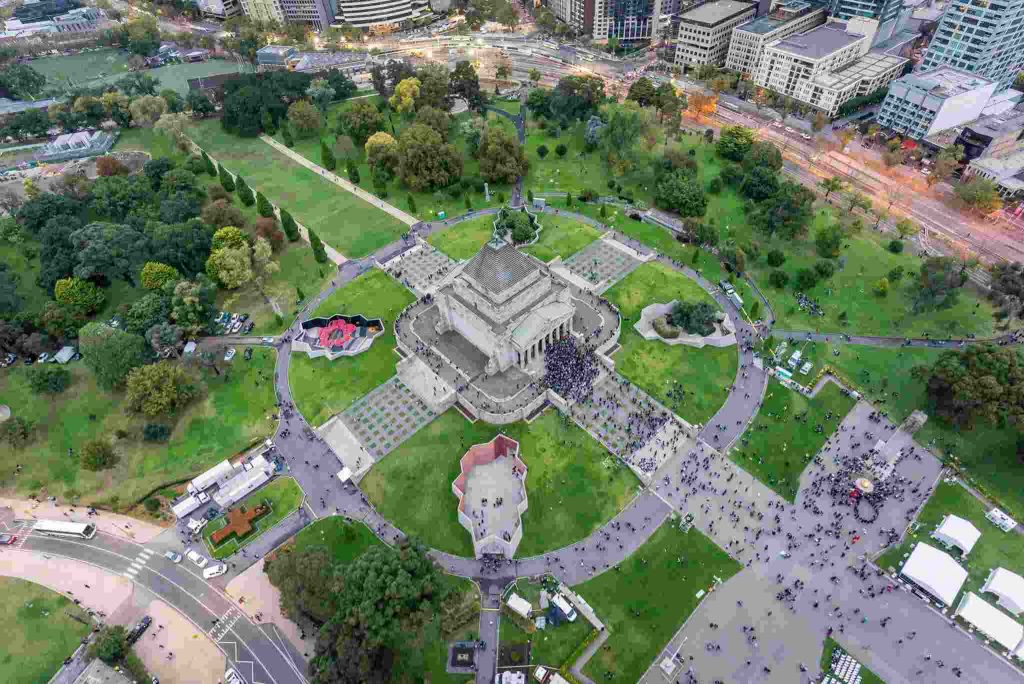 Aerial bird's-eye view of the Shrine of Remembrance monument surrounded by lush Kings Domain parklands in Melbourne.
