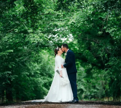 Bride and groom embracing in a lush green woodland forest setting during a wedding photo session at Narmbool.