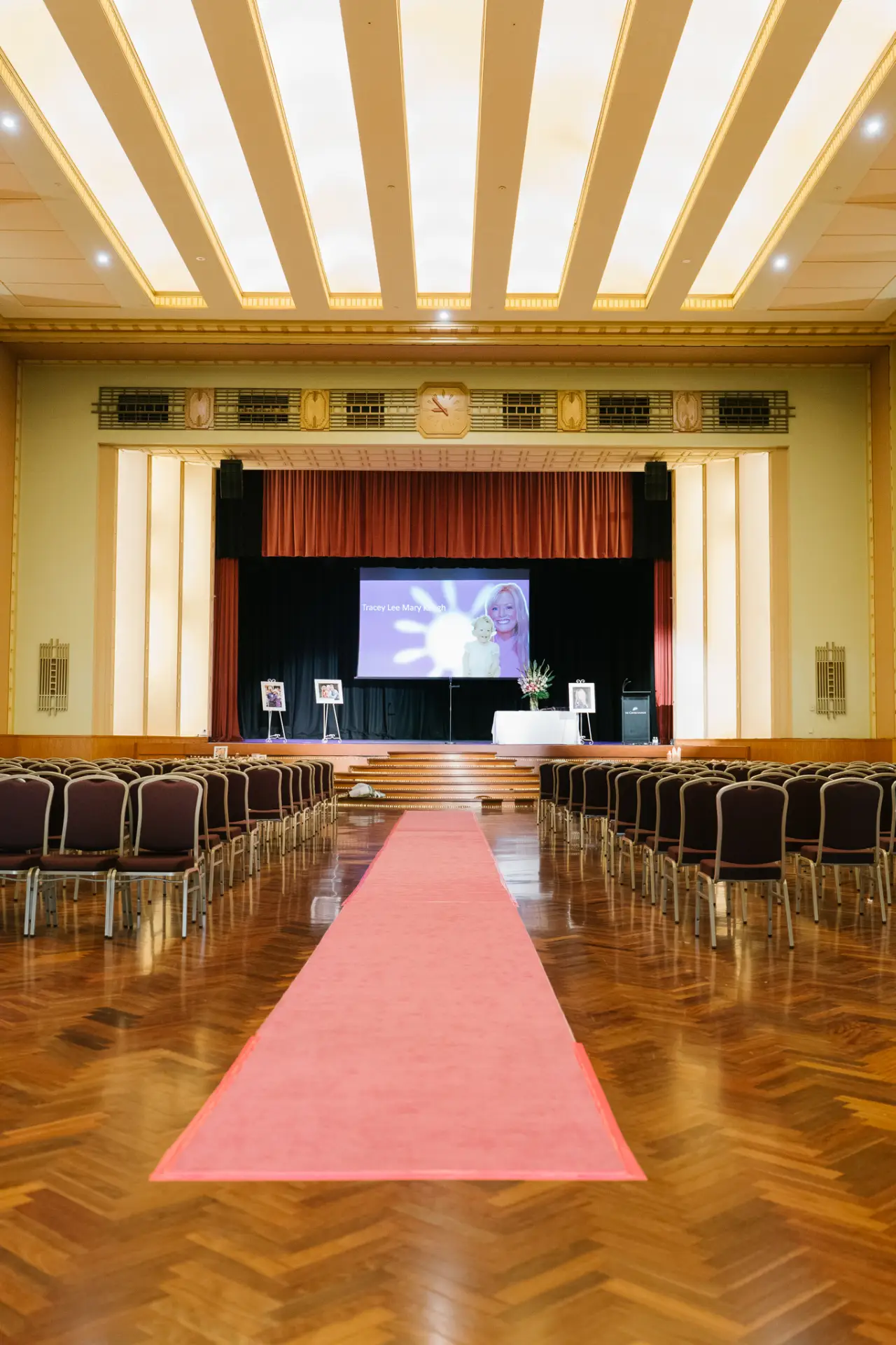 Red carpet aisle leading to a presentation stage in a theater-style conference setup at The Centre Ivanhoe.