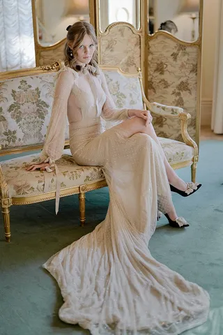 Guest in an elegant flowing gown seated on an antique gilt chaise lounge inside the historic Rippon Lea Estate mansion.