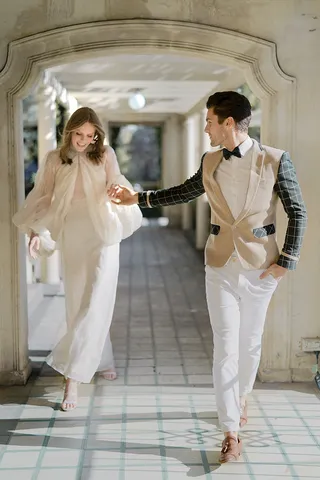 Couple in chic formal wear walking through the covered stone archway terrace at Rippon Lea Estate.