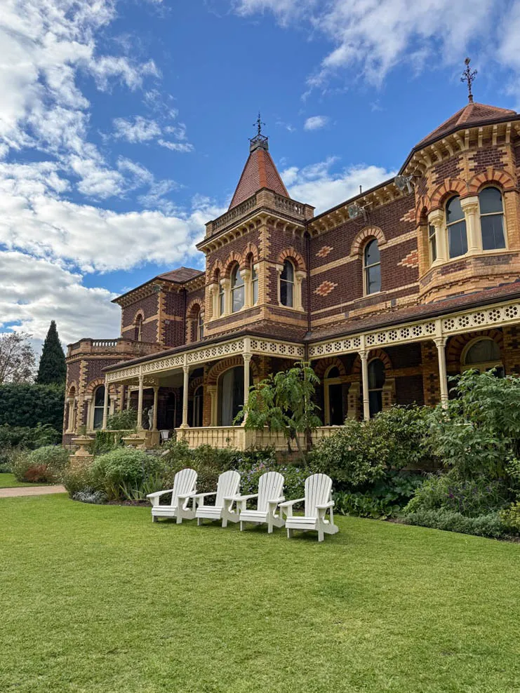 Rippon Lea Estate heritage mansion facade with white lounge seating set up on the expansive garden lawn.